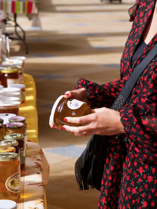 Femme avec en main, un pot de miel pris sur un stand lors du marché du Terroir à Contrexéville