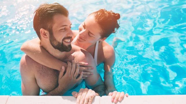 Cheerful youthful guy and lady resting while swimming pool outdoor. Couple in water.