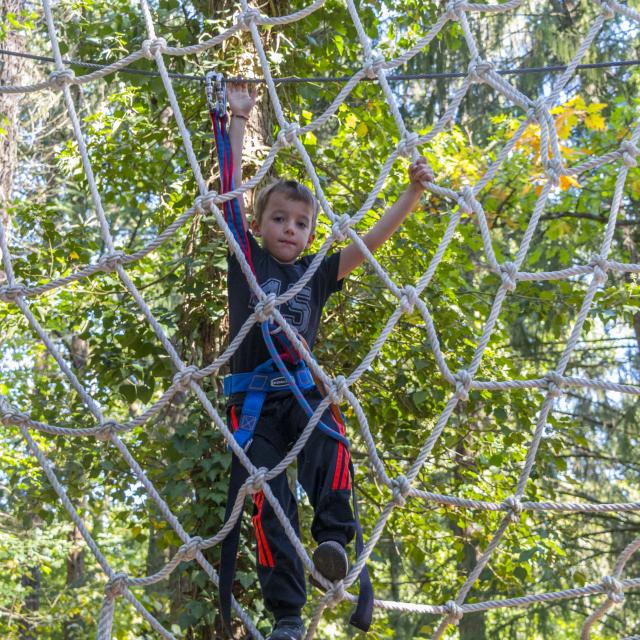 Enfant sur le pont de singe de l'accrobranche aux Lacs de la Folie à Contrexéville